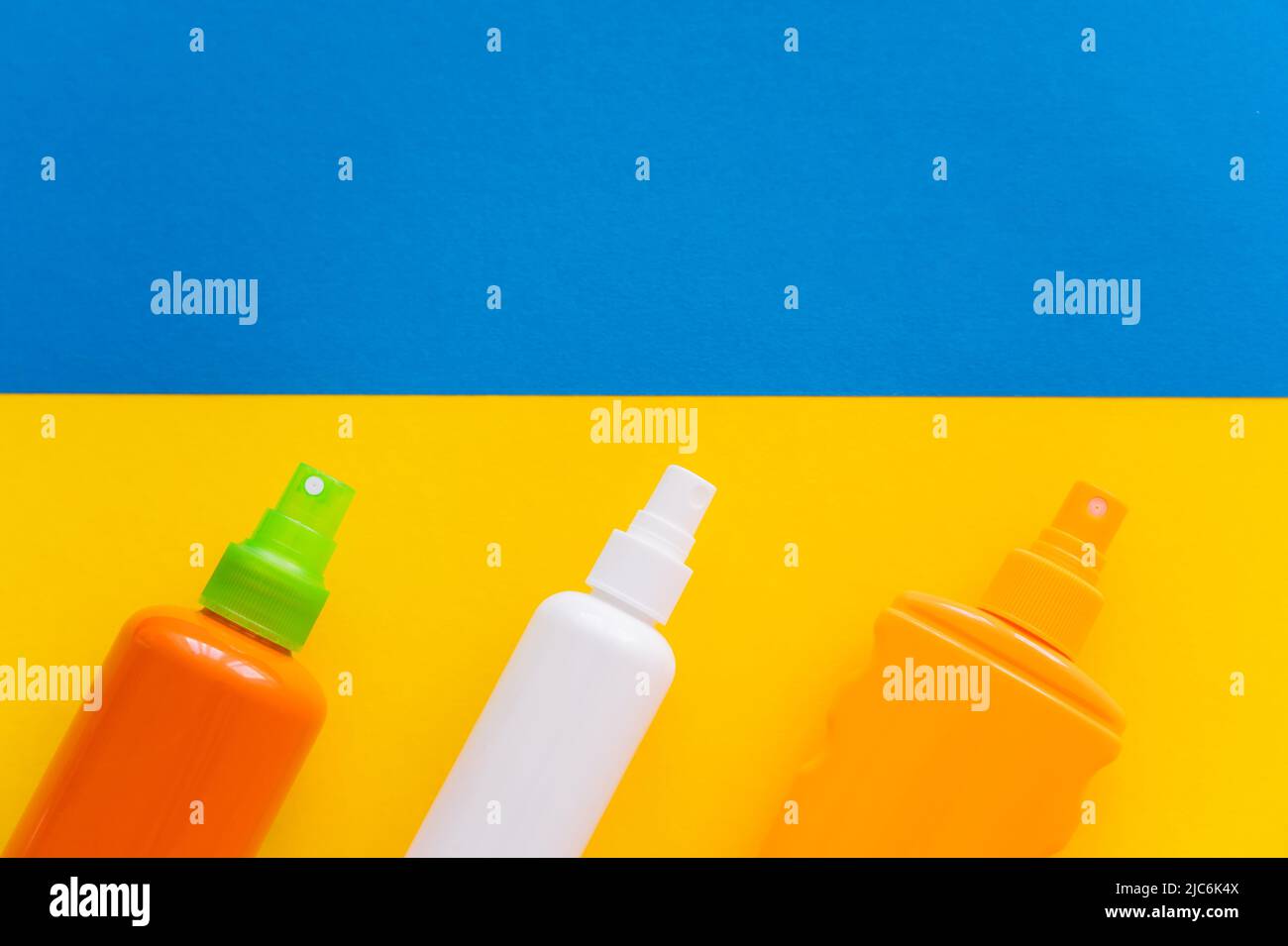 Top view of sunscreens on yellow and blue background Stock Photo