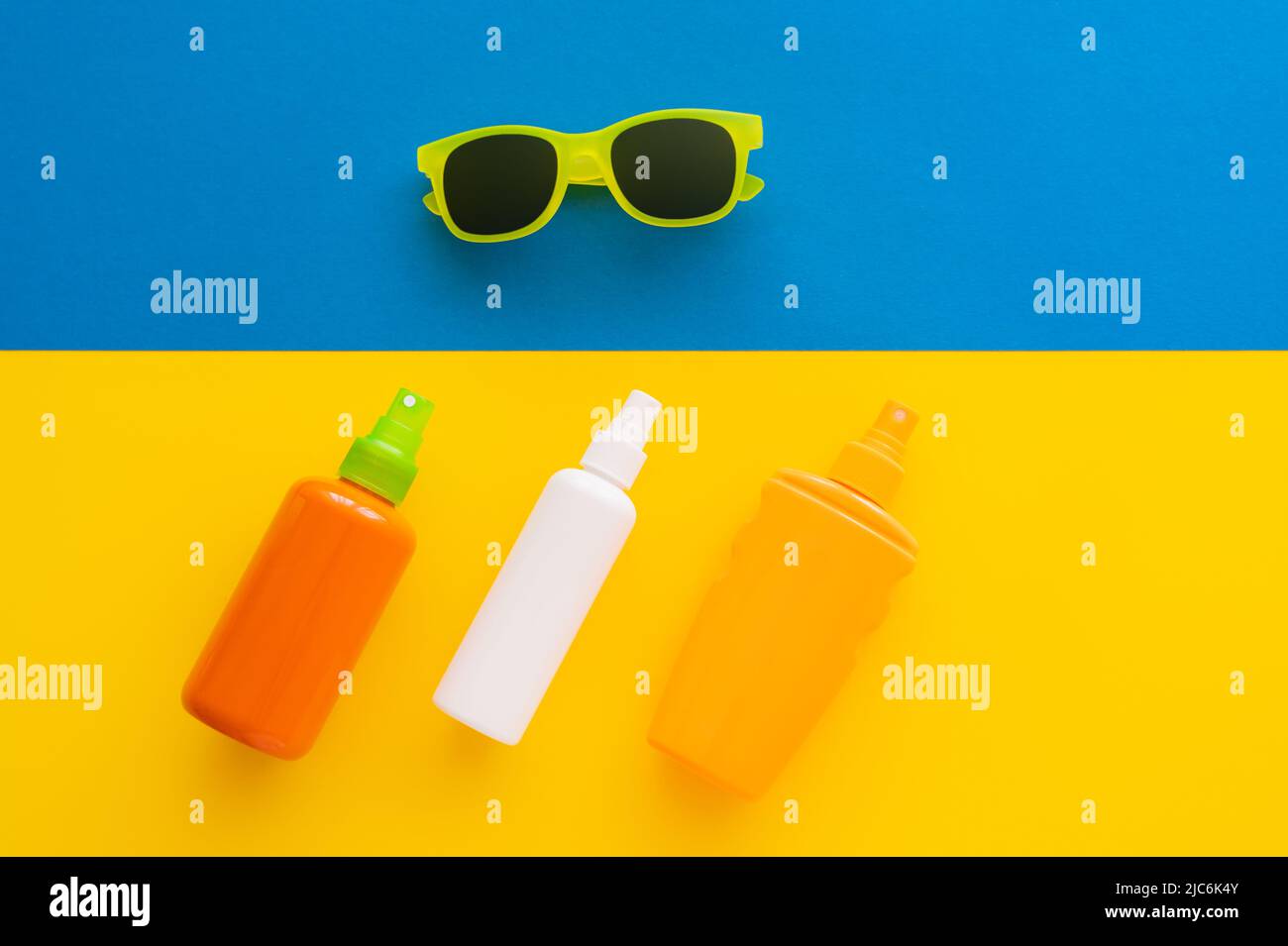 Top view of sunblocks and sunglasses on yellow and blue background Stock Photo