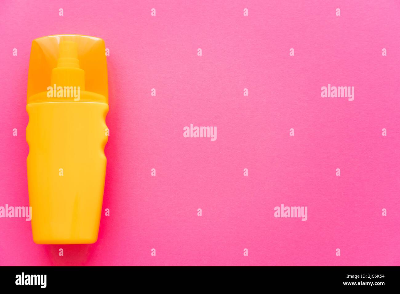 Top view of orange bottle of sunscreen on pink surface Stock Photo