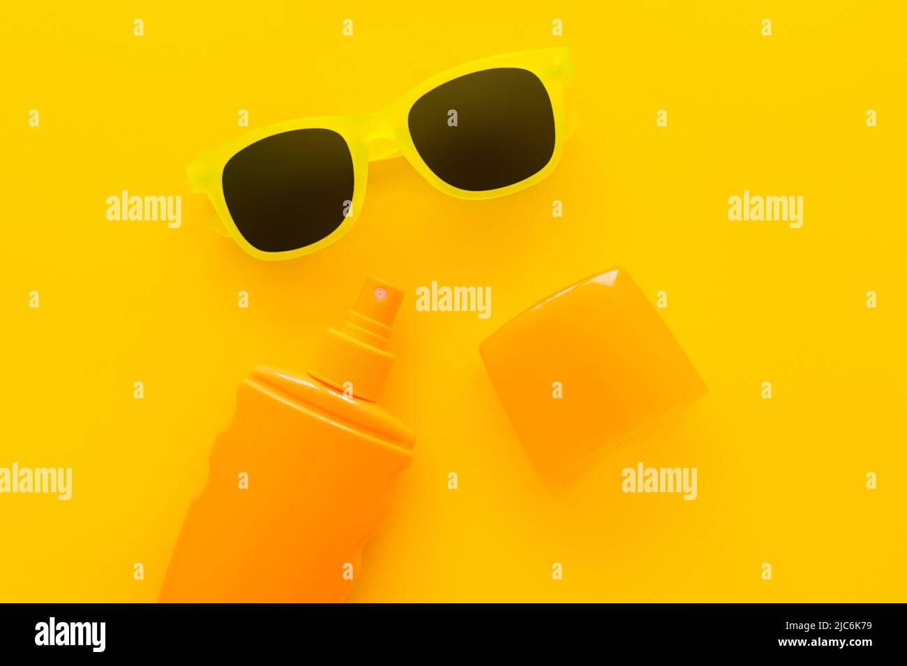 Top view of sunglasses and sunscreen on yellow background Stock Photo