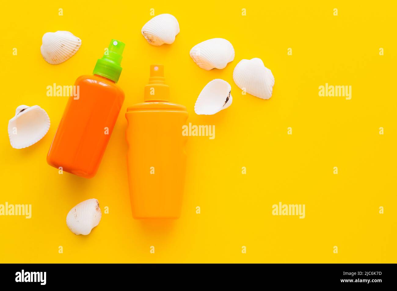 Top view of bottles of sunscreens near seashells on yellow background Stock Photo
