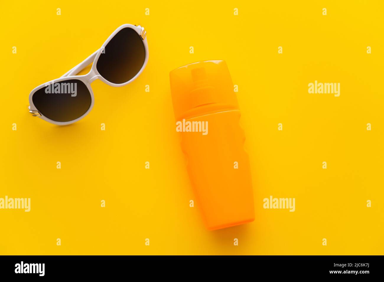 Top view of sunglasses near sunscreen on yellow background Stock Photo
