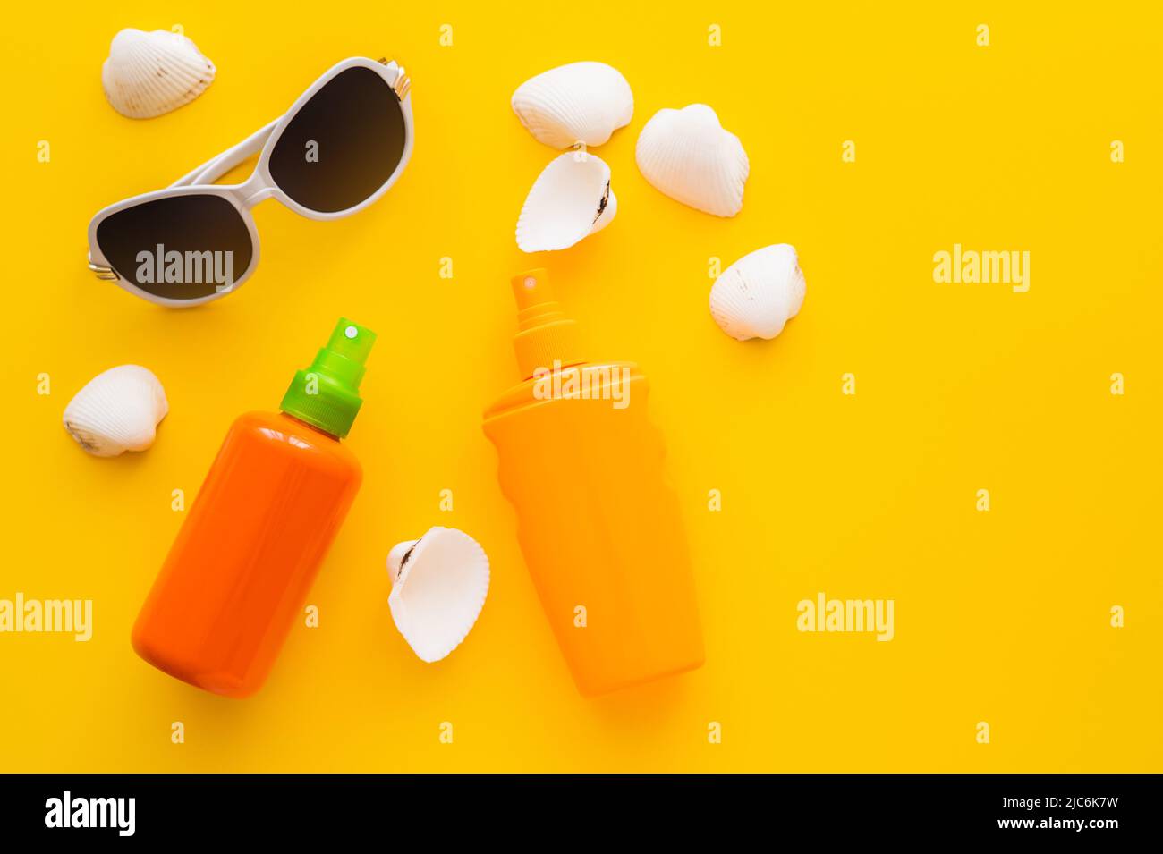 Top view of sunglasses near sunscreens and seashells on yellow background Stock Photo