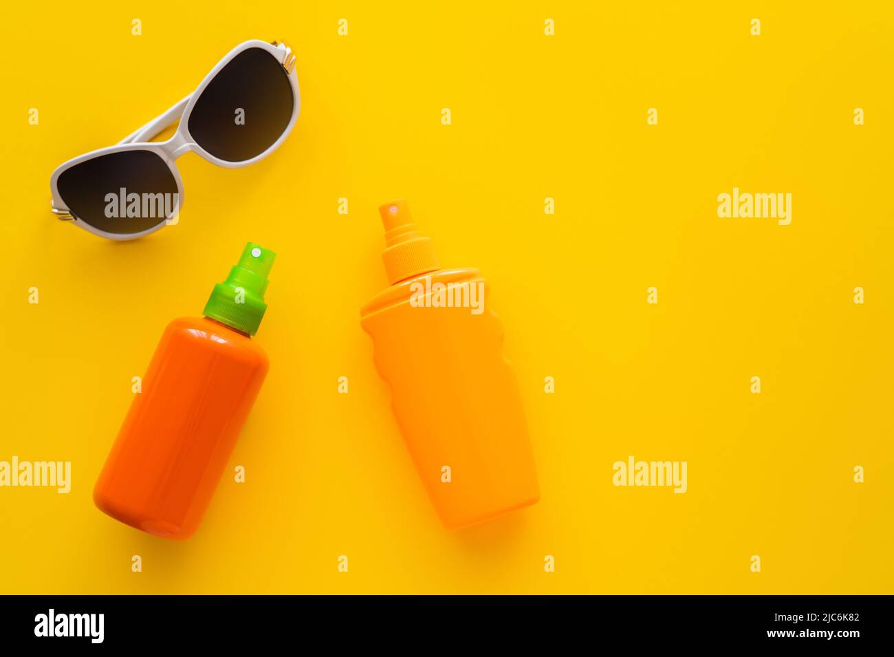 Top view of sunscreens near sunglasses on yellow background Stock Photo