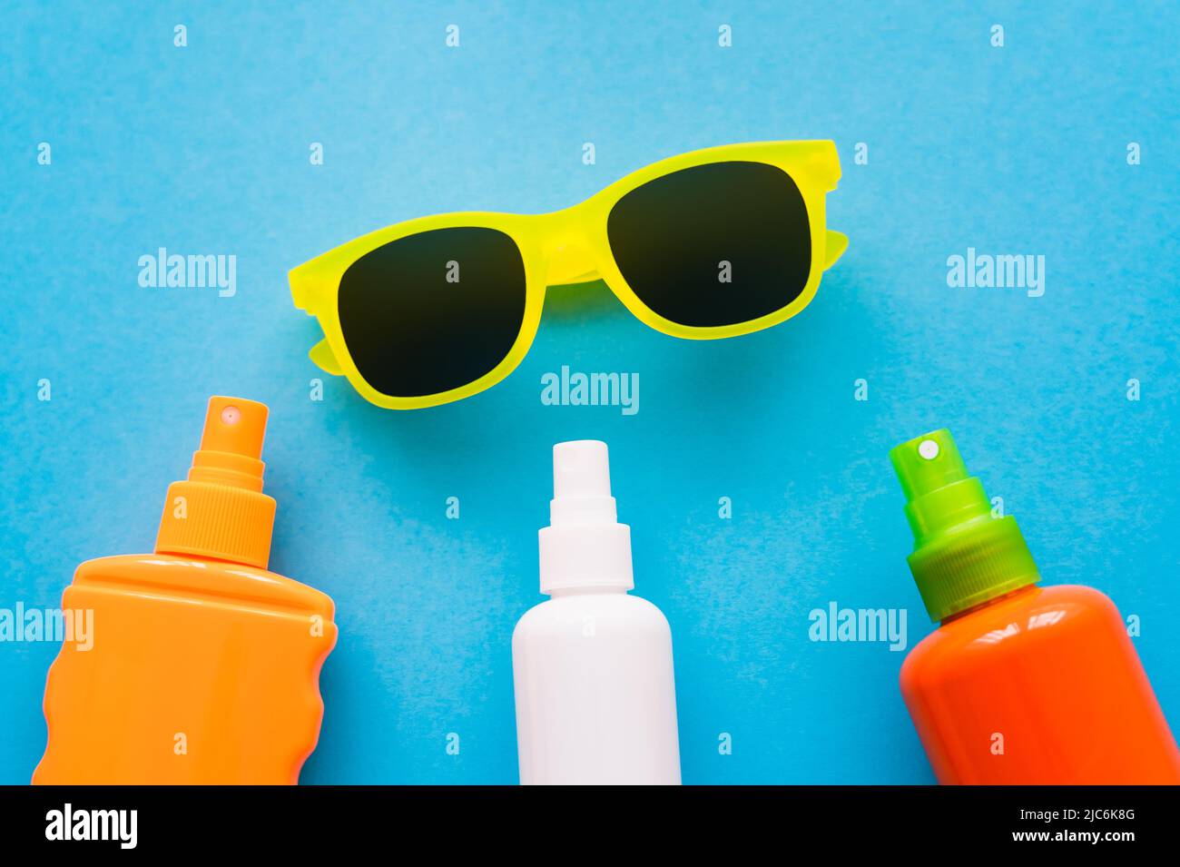 Top view of sunglasses near bottles of sunscreens on blue background Stock Photo