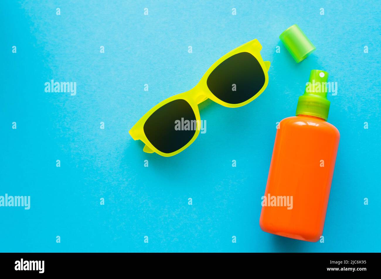Top view of sunglasses near bottle of sunblock on blue background Stock Photo