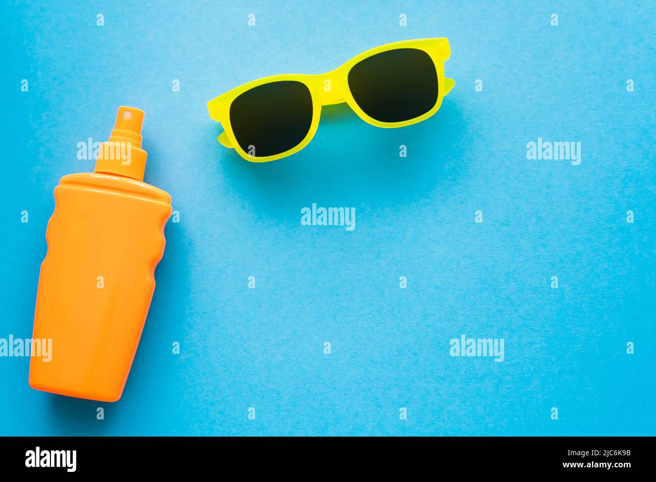 Top view of sunscreen and sunglasses on blue background Stock Photo