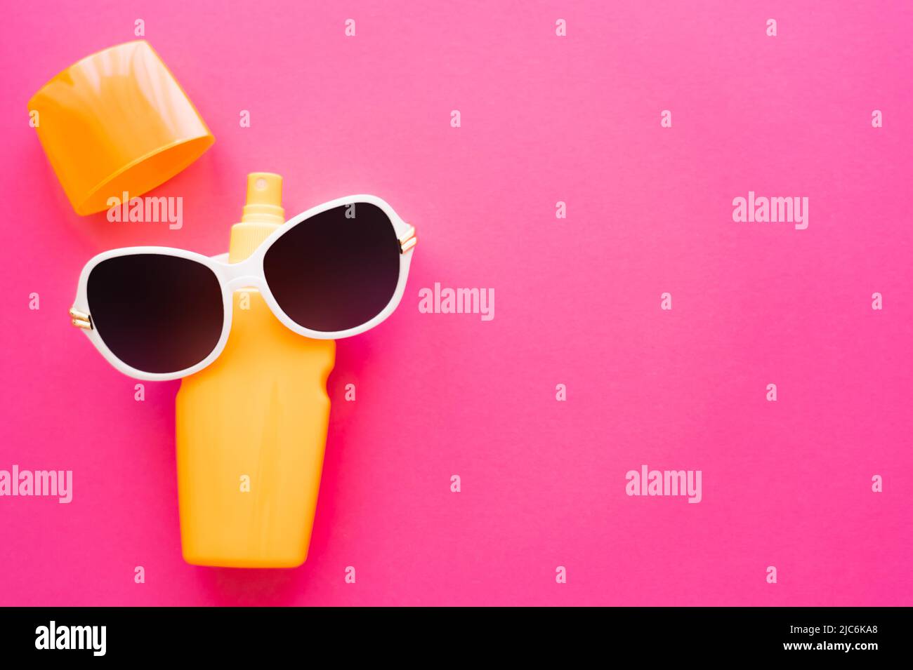 Top view of sunglasses on sunscreen on pink surface Stock Photo