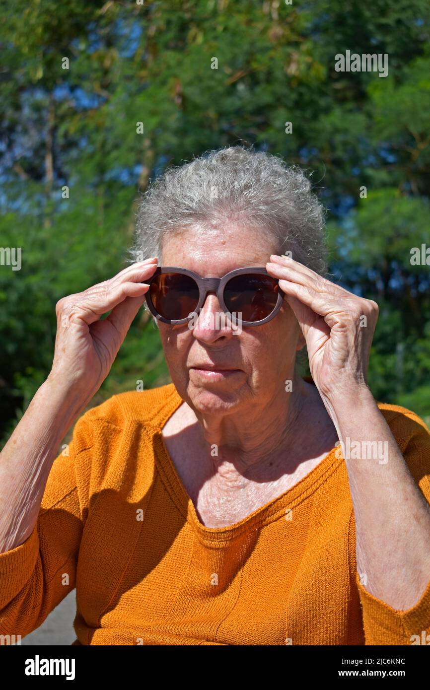 Elderly woman putting on sunglasses Stock Photo Alamy
