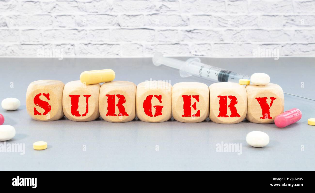 The word SURGERY is written on wooden cubes near a stethoscope on a wooden background. Stock Photo