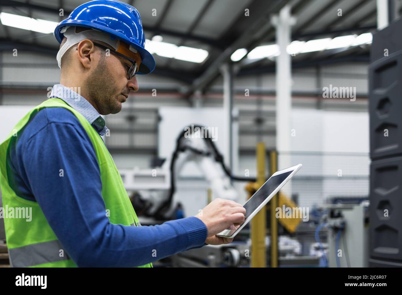 Engineer man working in robotic factory while monitoring the project on smart tablet - Tech industry concept Stock Photo