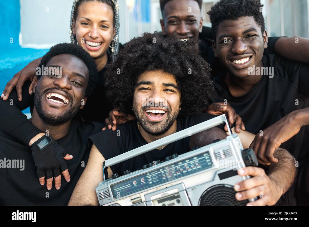 Happy group of multiracial people having fun listening music with vintage boombox outdoor - Youth people lifestyle Stock Photo