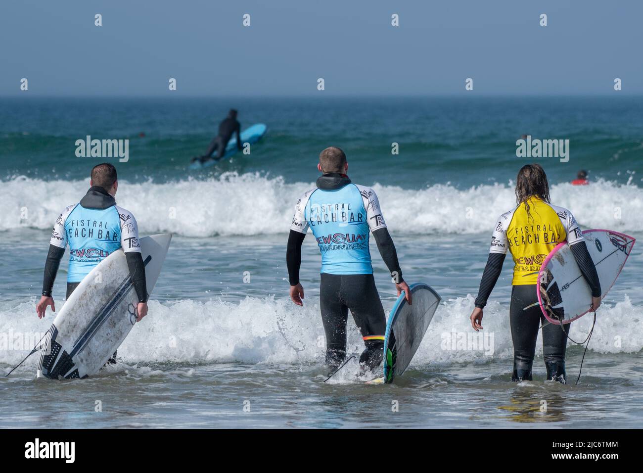 Three male surfers at the start of a surfing competition at Fistral in