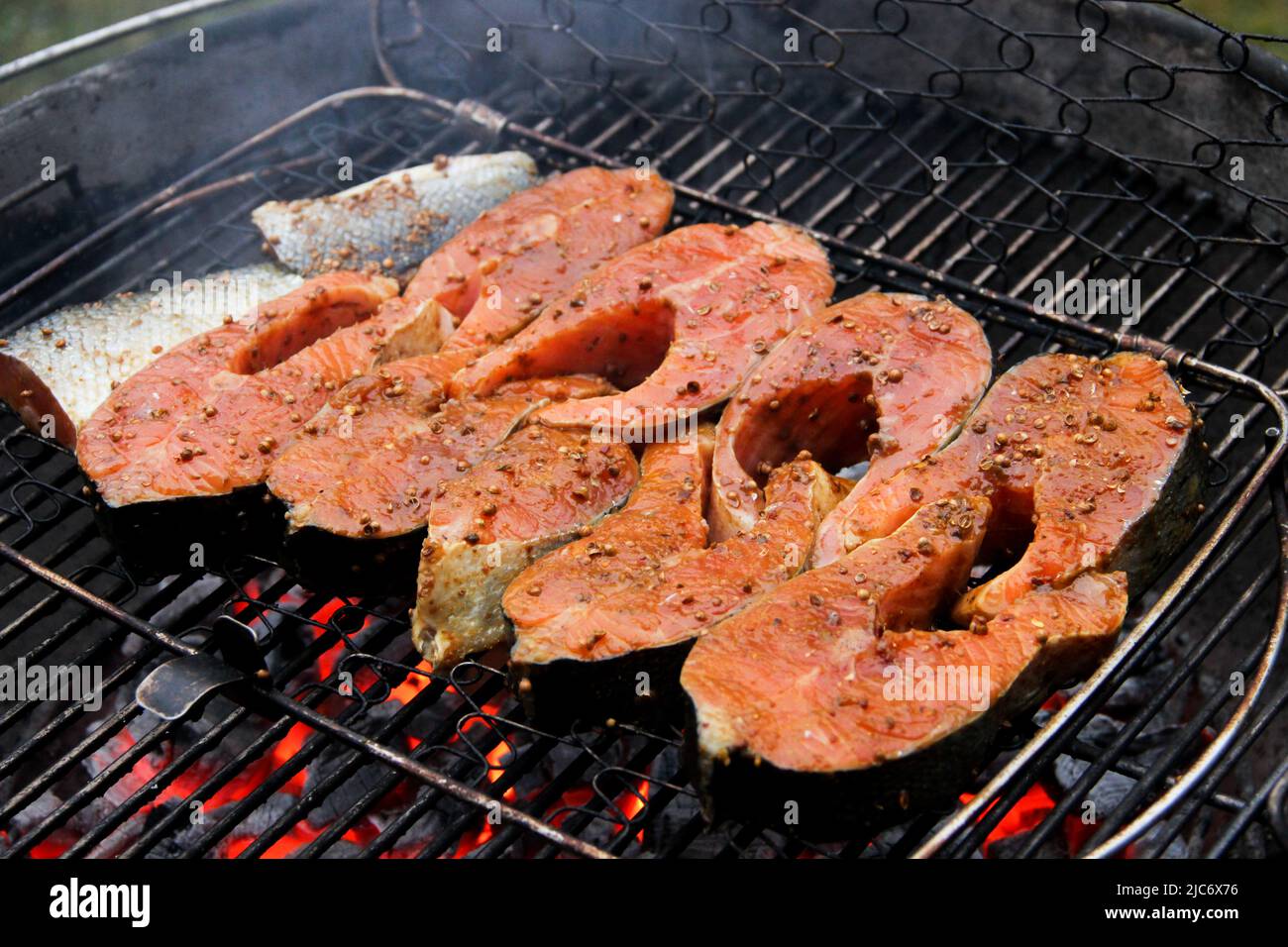 Salmon filet on a barbeque grid. Redfish steaks in the marinade over hot coals. Close-up of grilled salmon steaks. Stock Photo
