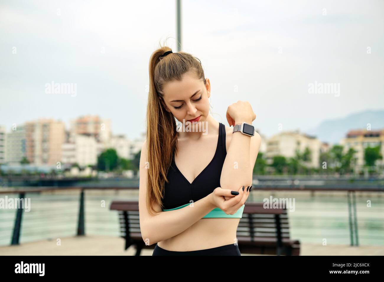 Cute brunette woman wearing sports bra standing on city park