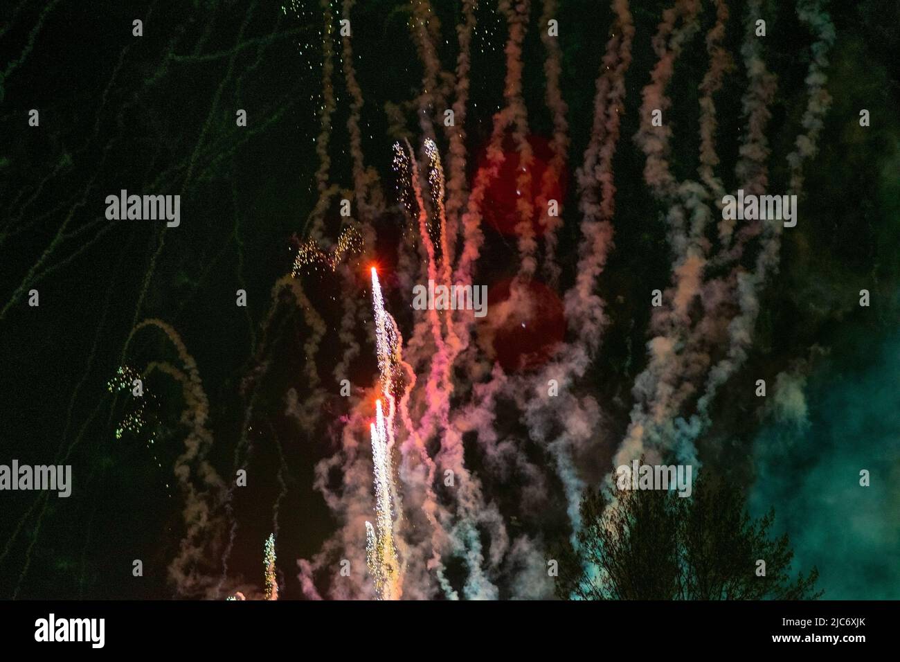 Flying up, bright volleys of fireworks, red and white, against the background of haze and the night sky. High quality photo Stock Photo