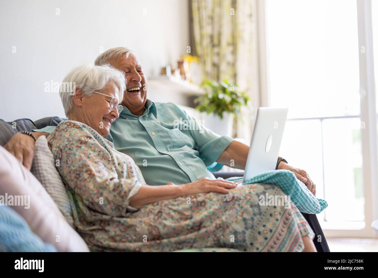 Happy senior couple using laptop at home Stock Photo
