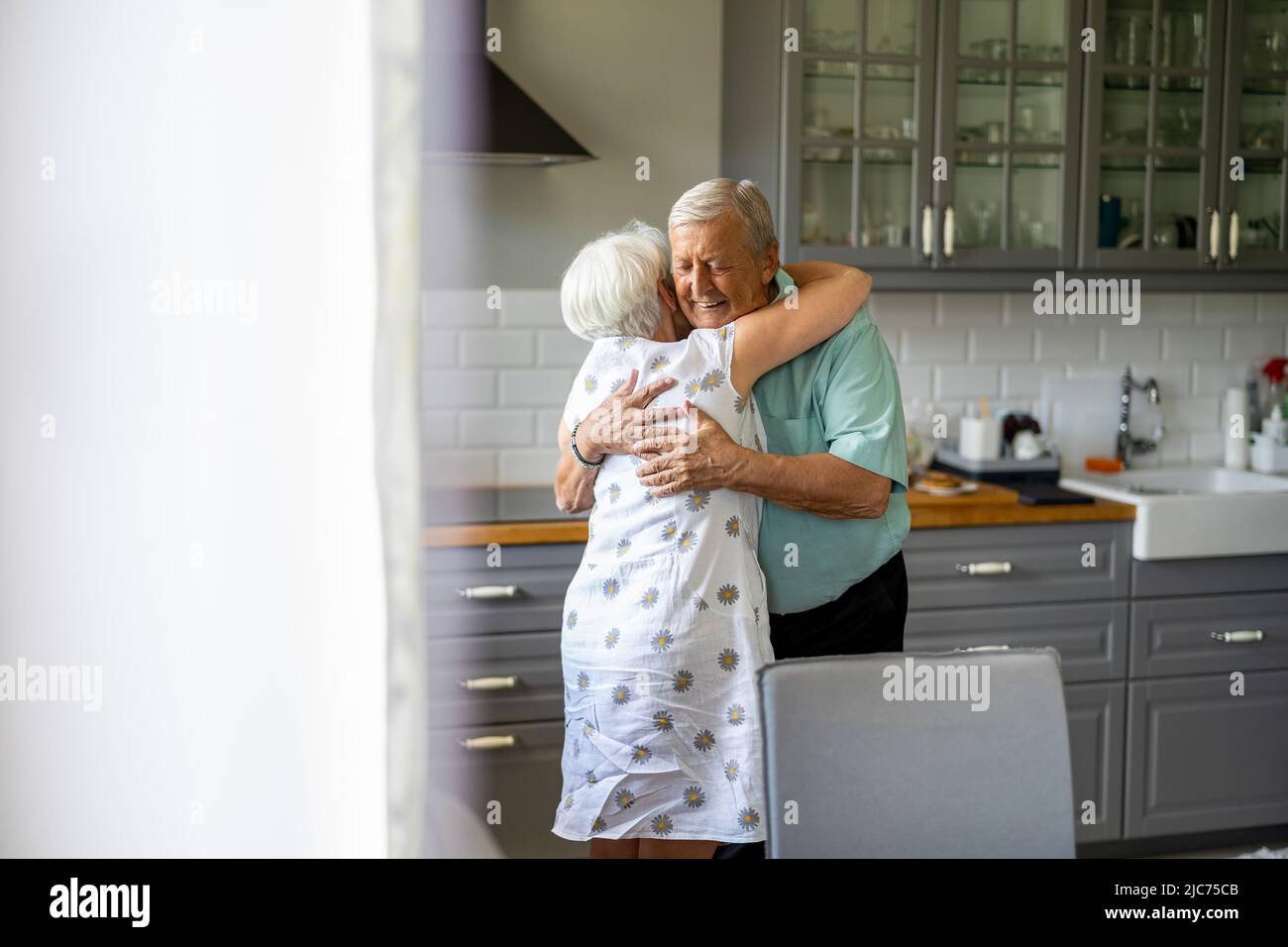 Senior Couple Hugging in their Kitchen Stock Photo