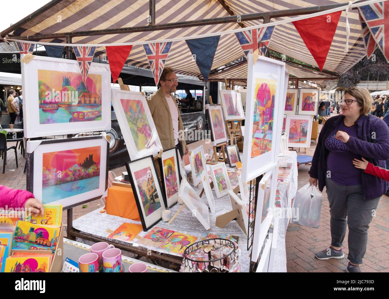 Woman shopping for a picture at an artist's market stall, Ely market, Ely Cambridgeshire UK Stock Photo