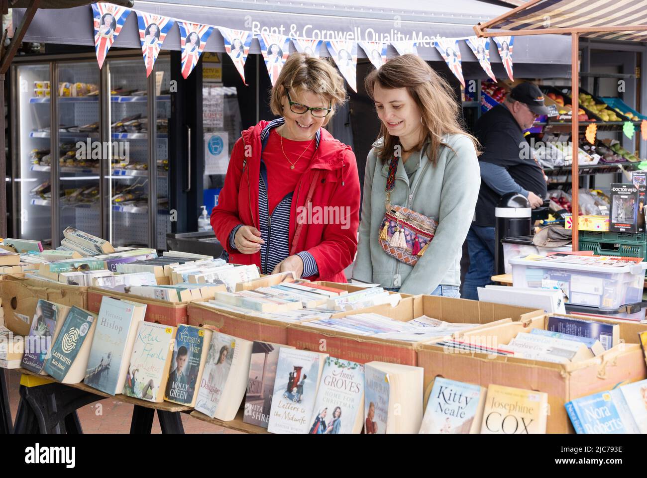 Market UK; Second hand book stall UK; two women shopping for second hand books at a market stall, Ely Market, Ely Cambridgeshire UK Stock Photo