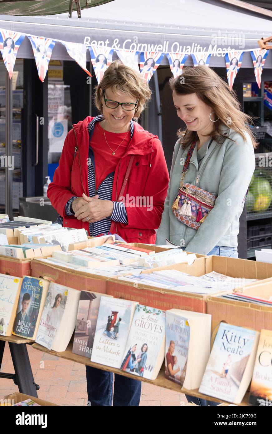 Market UK; Second hand book stall UK; two women buying second hand books at a market stall, Ely Market, Ely Cambridgeshire UK Stock Photo