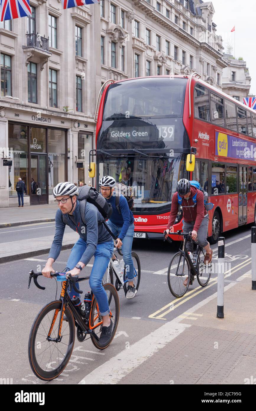 London cycling - three men cycling in London, in front of a london bus; Regent Street, London UK Stock Photo