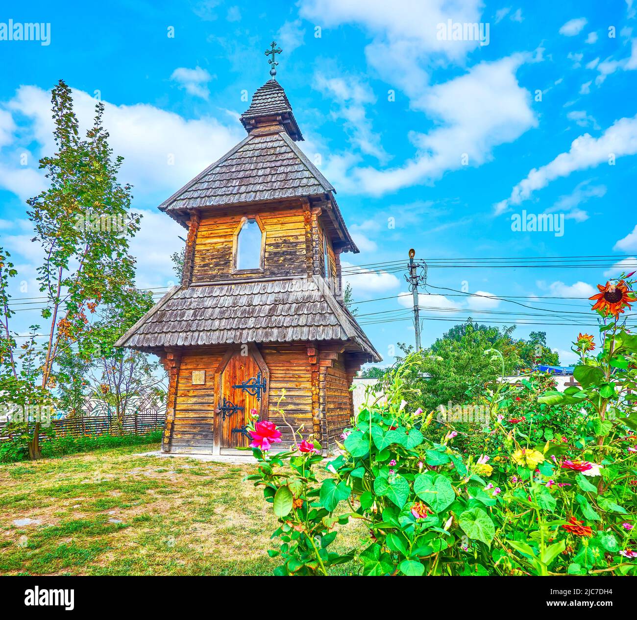 The old wooden church and the garden with blooming flowers, during National Sorochynsky Fair, Ukraine Stock Photo