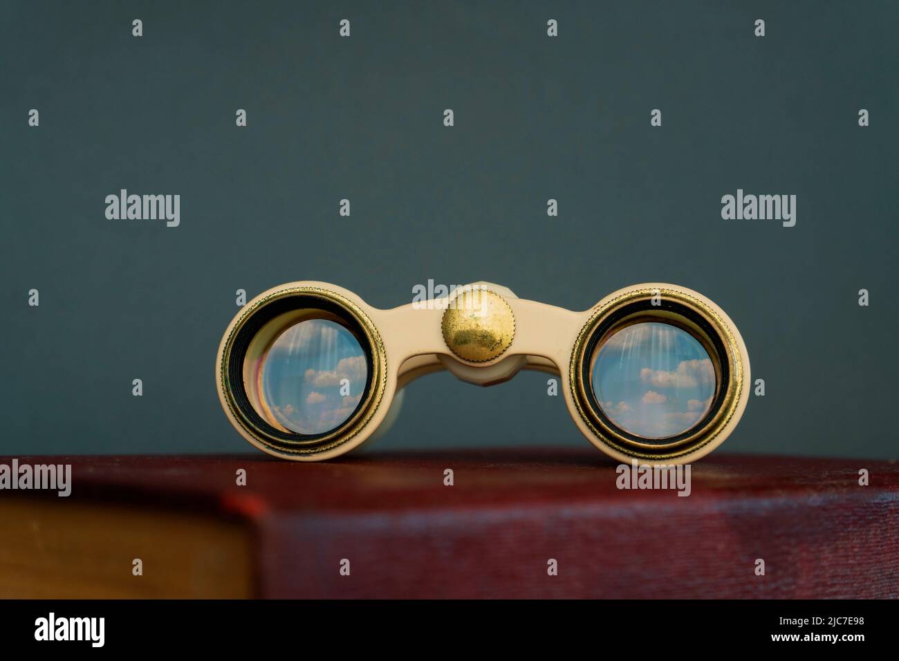 Binocular on a book isolated, cloud reflection on binocular's glass
