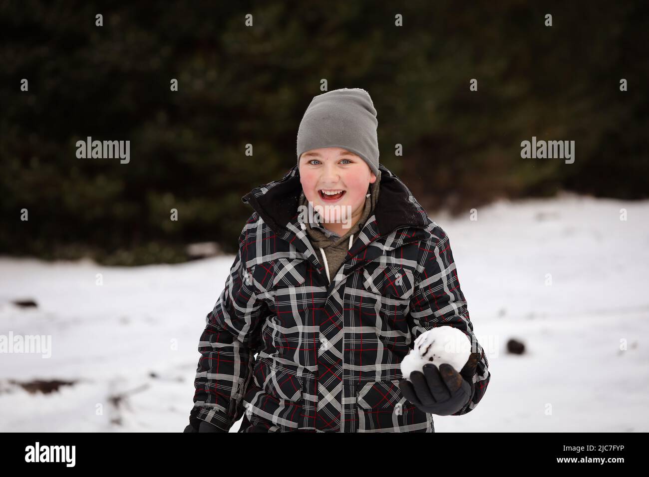 Boy in the snow with snow ball having snowball fight Stock Photo