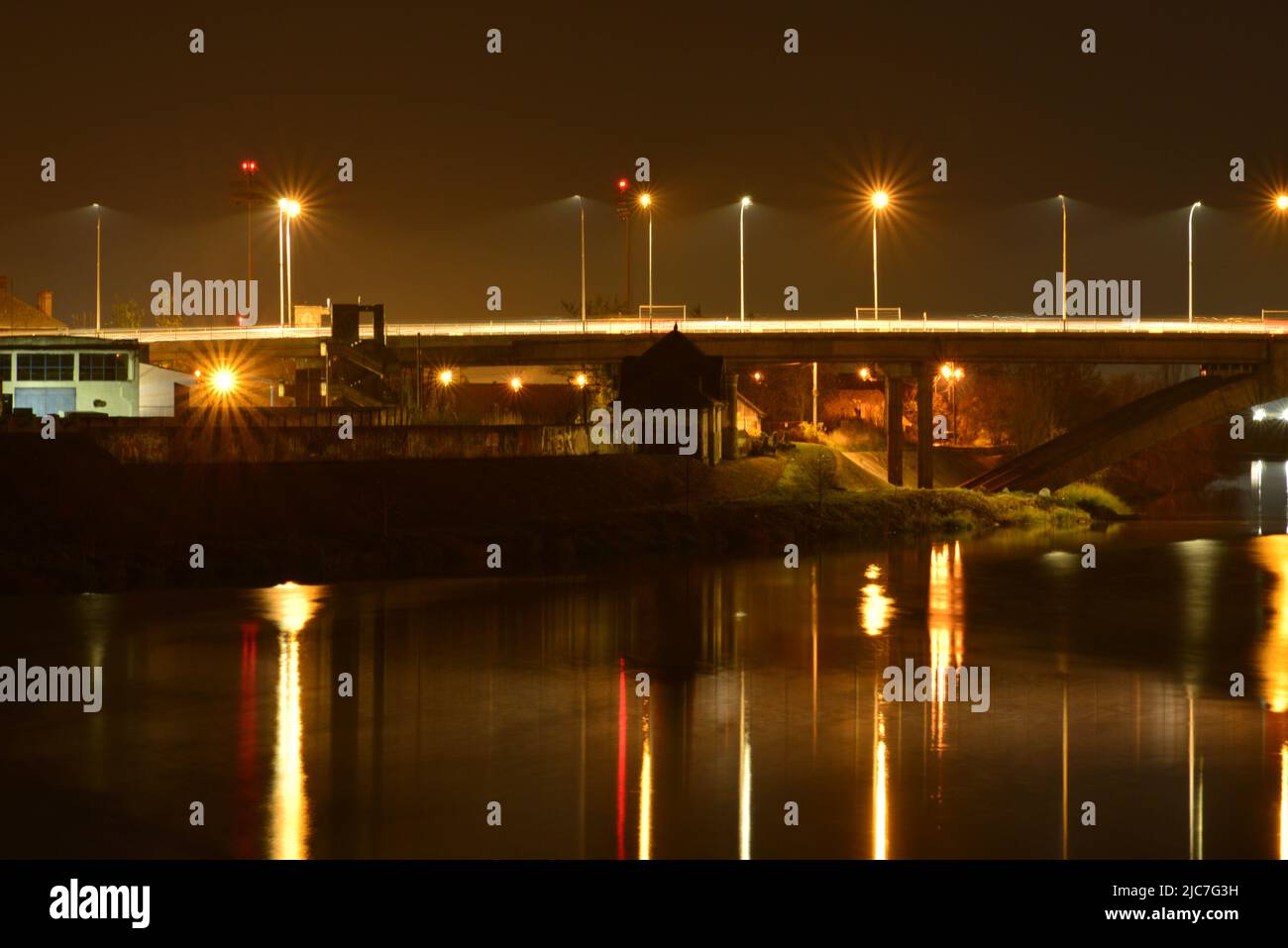 Night landscape of bridge and lampposts reflected in the river Stock Photo