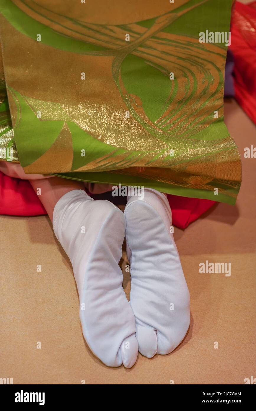 Close up on the backside of a Japanese maiko or geisha woman's feet wearing traditional white socks called tabi worn with thongs footwear such as geta Stock Photo