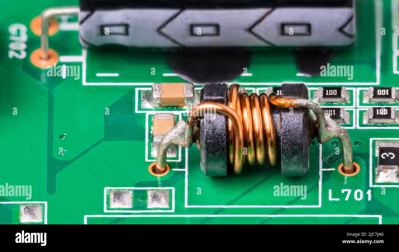 Green PCB detail. Electromagnetic coil and electronic surface-mount components. Closeup of inductor with copper wire on ferrite core. Electrotechnics. Stock Photo