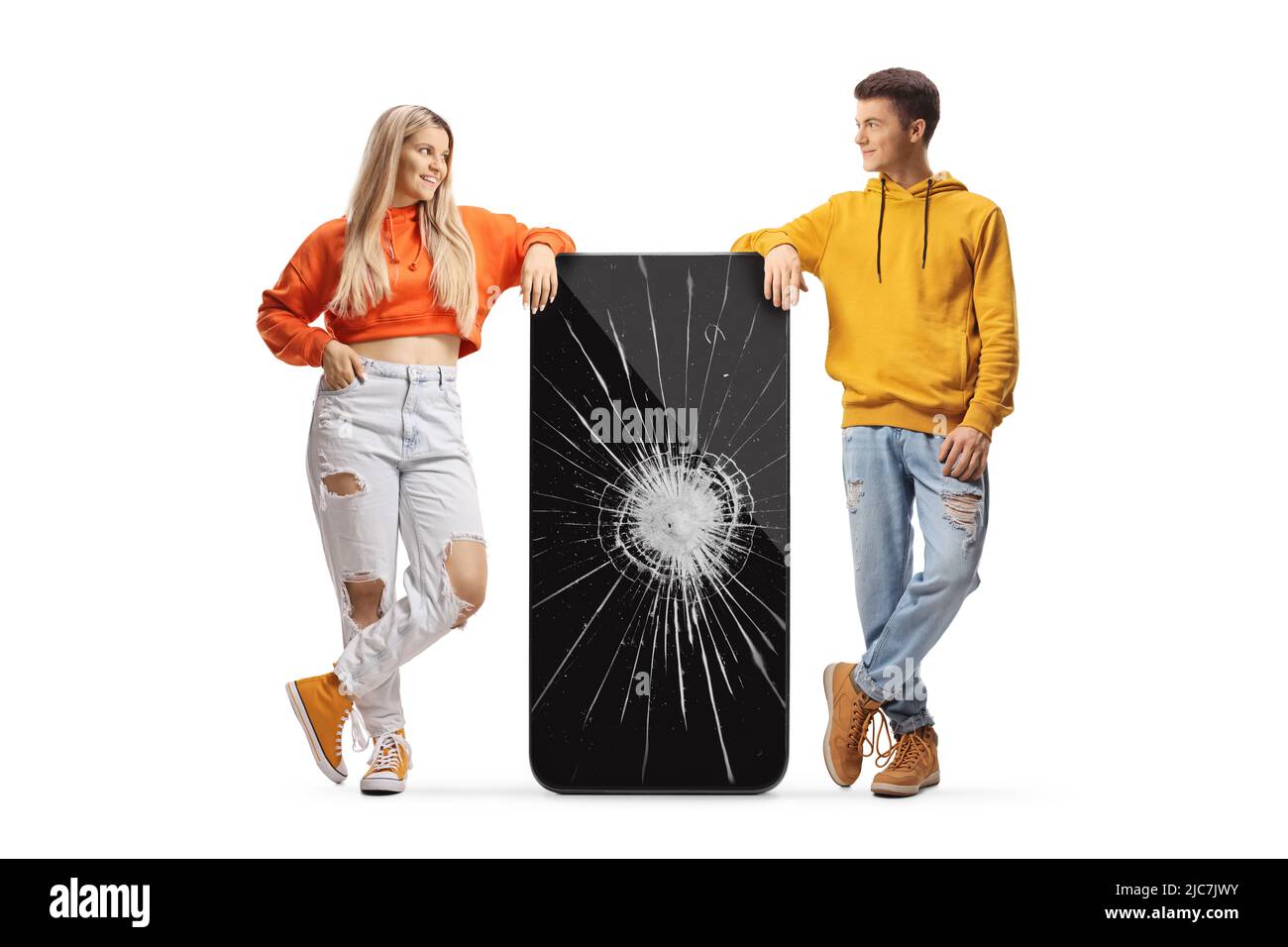 Young trendy girl and guy leaning on a big mobile phone with crushed screen isolated on white background Stock Photo