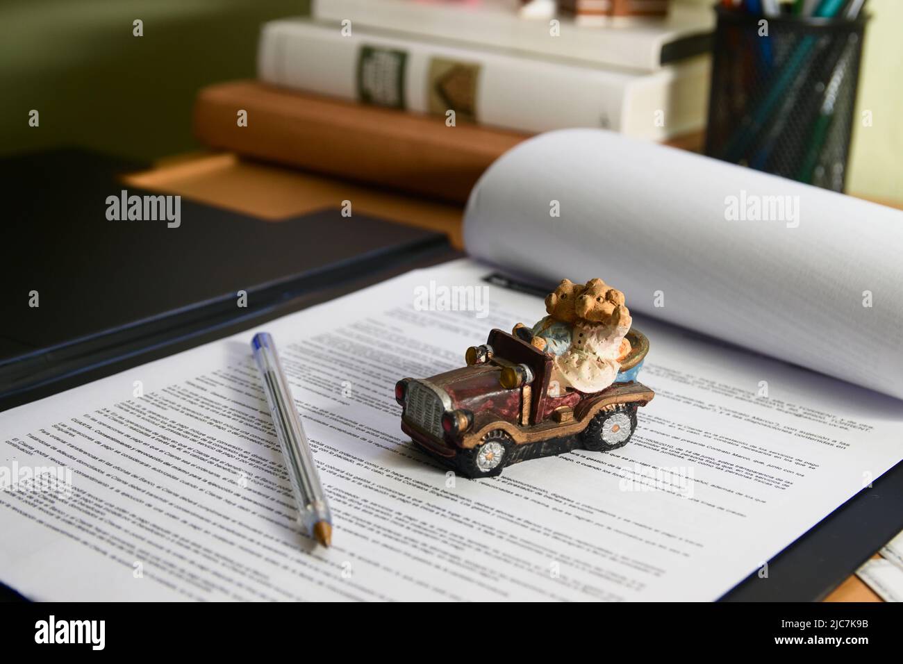 Image of a stroller on a car purchase agreement on a table in an office, with out-of-focus books in the background Stock Photo