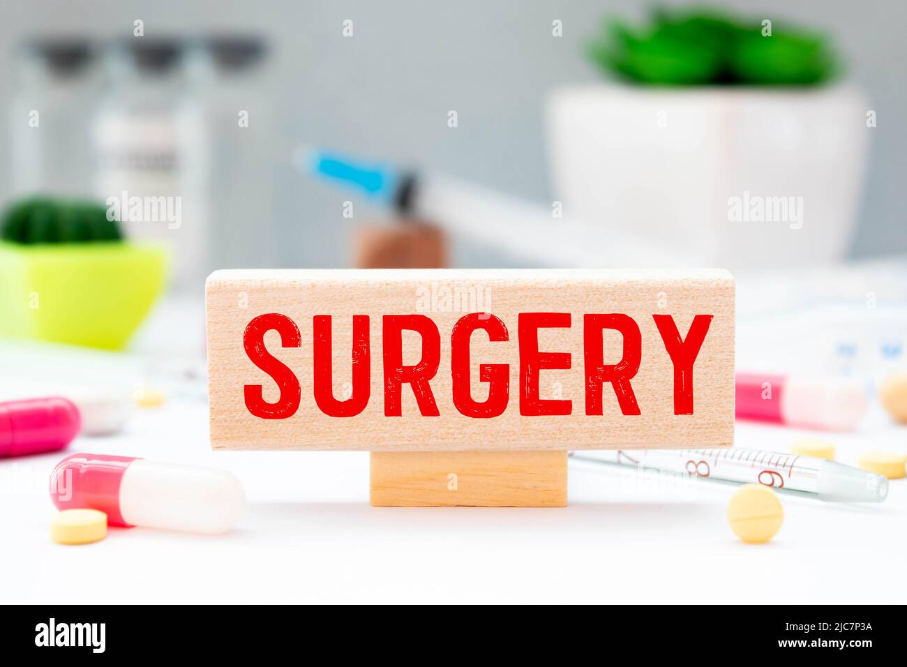 The word SURGERY is written on wooden cubes near a stethoscope on a wooden background. Stock Photo