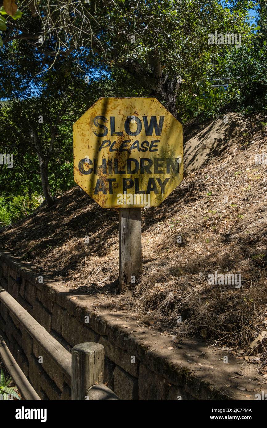 A warning sign 'Slow please children at  play that is weathered from the amount of time it has been in use in Santa Barbara County, California. Stock Photo