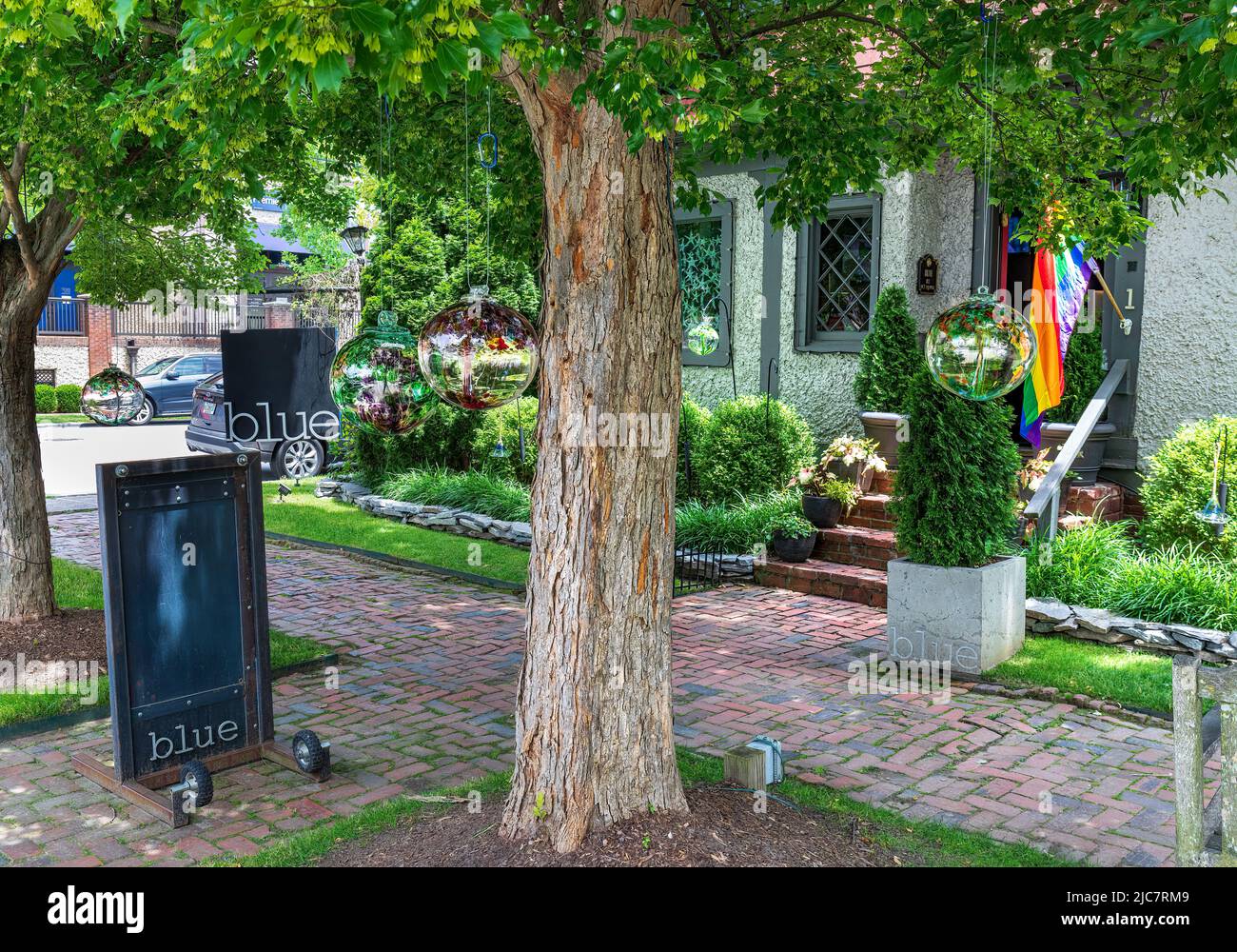 BILTMORE VILLAGE in ASHEVILLE, NC, USA-5 JUNE 2022: The Blue Goldsmith shop entrance, with multiple colorful glass globes hanging in shady foreground. Stock Photo