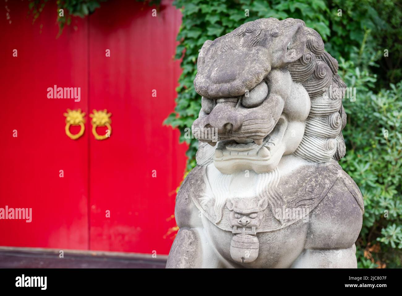 Chinese lion stone statue and red door Stock Photo