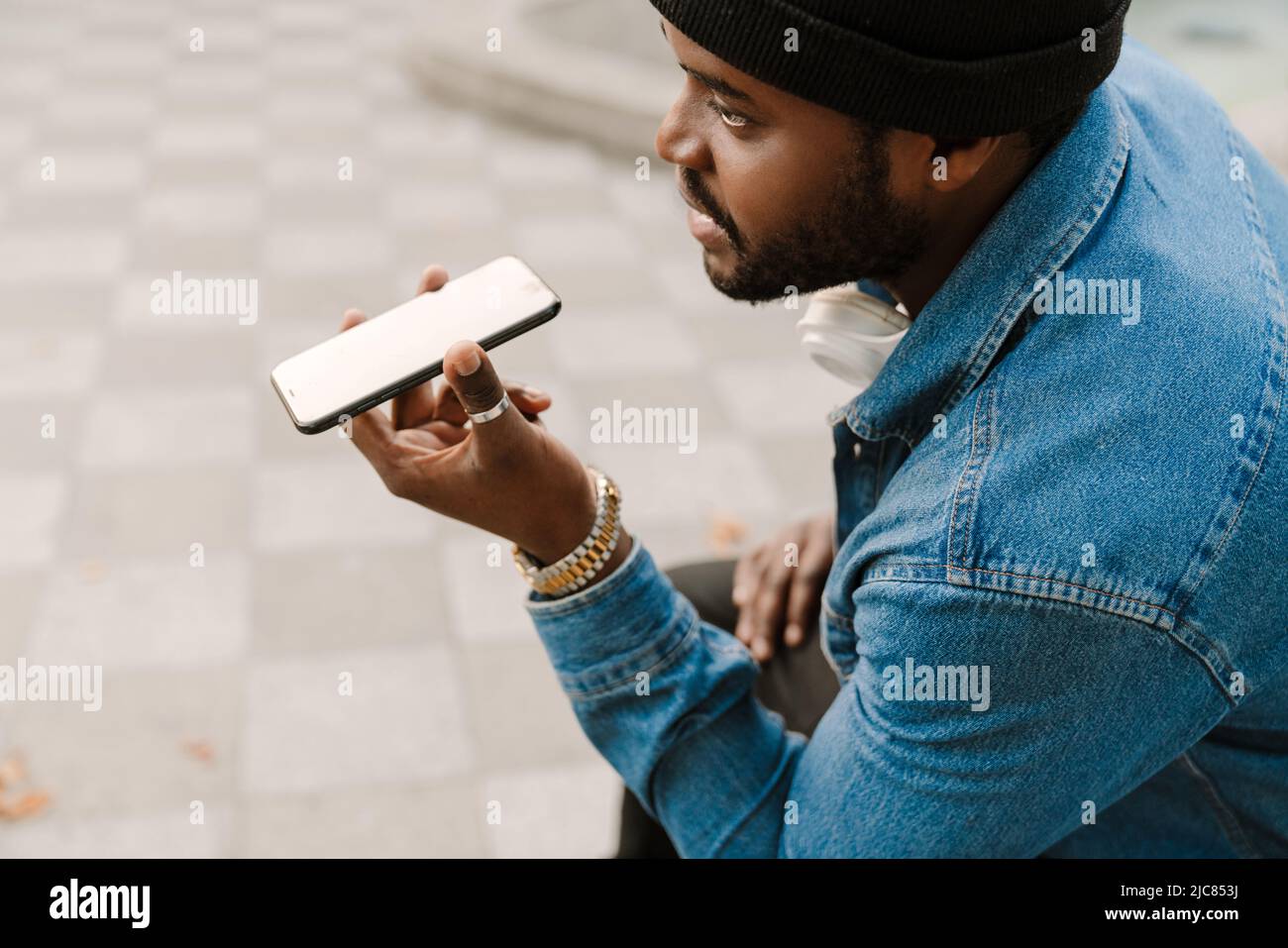 Black young man with headphones talking on mobile phone outdoors Stock Photo