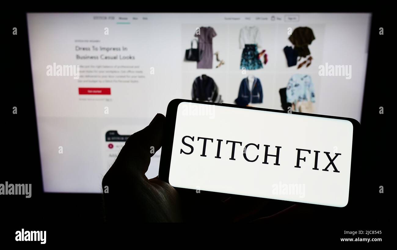 Person holding smartphone with logo of US styling company Stitch Fix Inc. on screen in front of website. Focus on phone display. Stock Photo