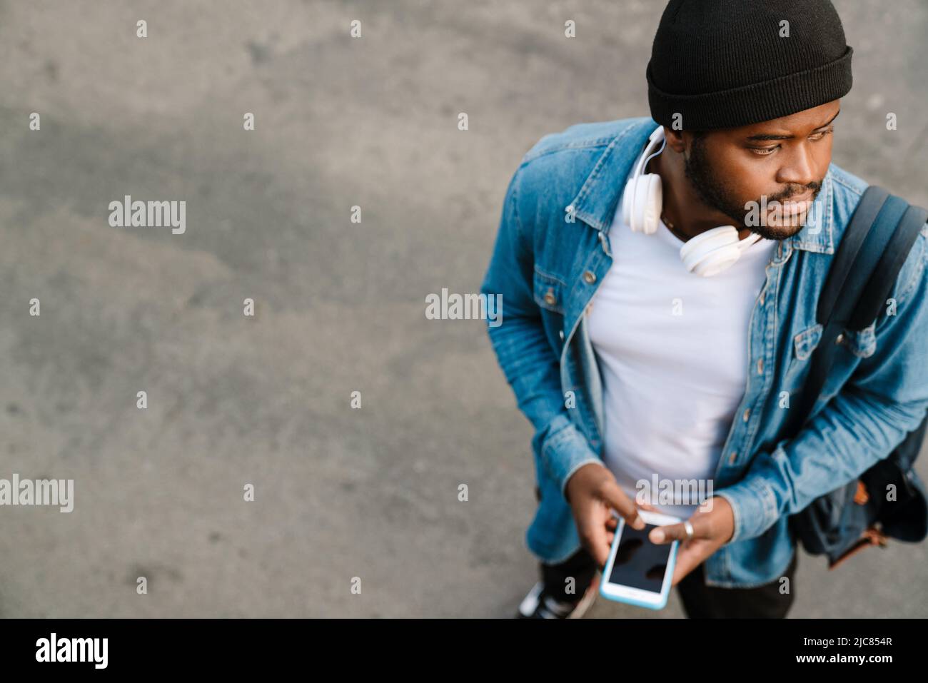 Black man with headphones using mobile phone while standing outdoors Stock Photo