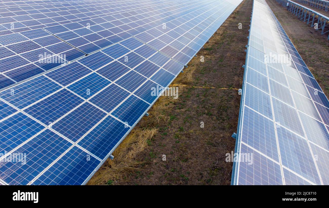 Aerial drone view flight over solar power station panels. Aerial top view of solar farm. Green energy, electrical innovation. Renewable Energy. Industrial Solar Energy Farm producing solar power. Stock Photo