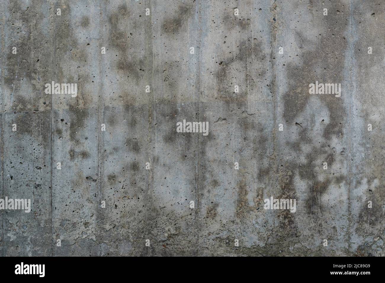 Texture of old reinforced concrete surface. Flat reinforced concrete surface with traces of wooden formwork, covered with dark spots, background. Stock Photo