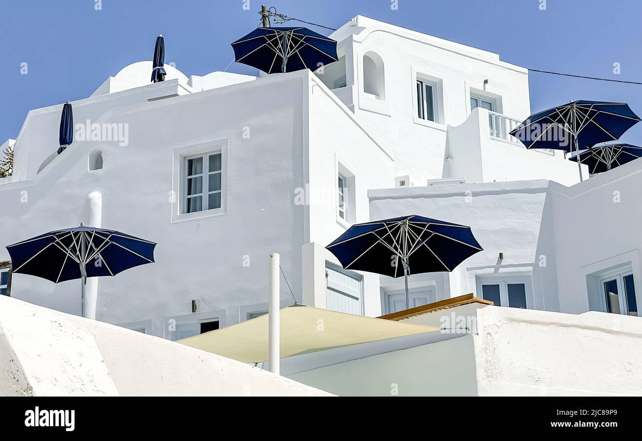 Elegant blue parasols on terraces on different levels in Imerovigli on Santorini island form a geometric pattern Stock Photo