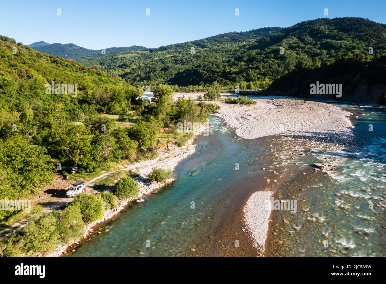 Camping with off road vehicle and roof tent on a wild mountain river with gravel bed in Greece