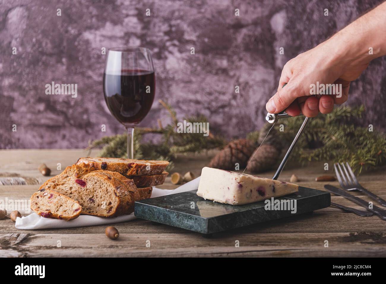 Wensleydale cheese with cranberries, red wine, honey, nuts, raisins on marble cutting board. Black concrete background. Selective focus. Stock Photo