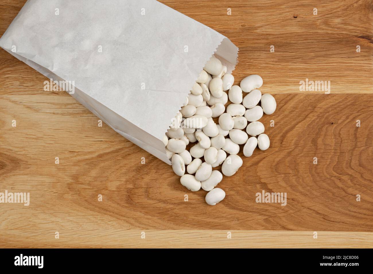 white kidney beans poured out of paper bag on wooden background