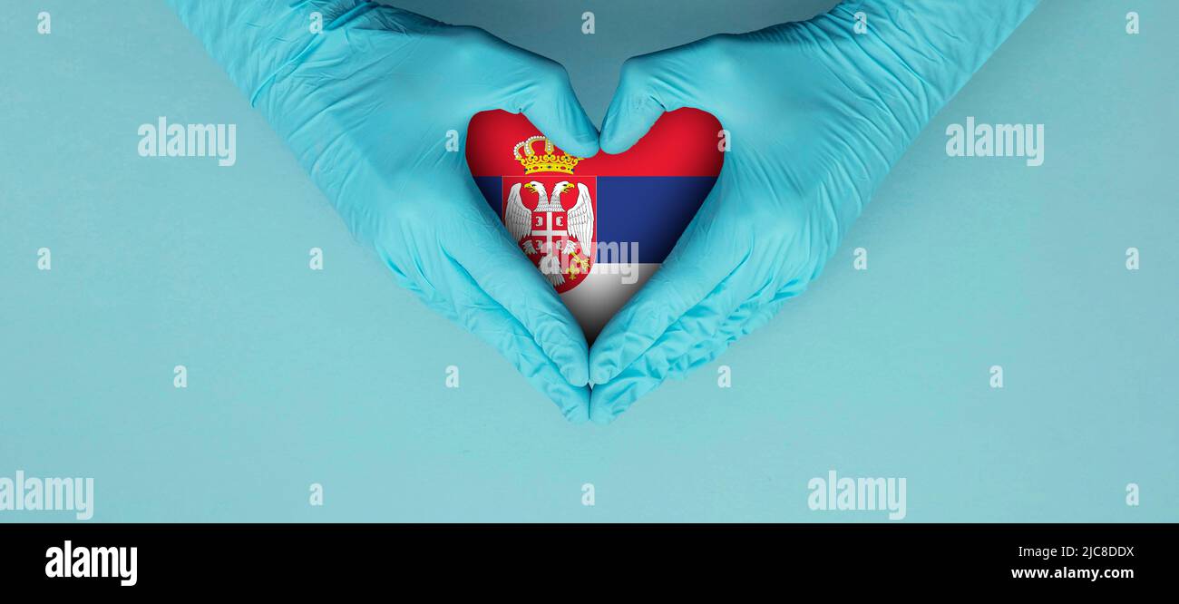 Doctors hands wearing blue surgical gloves making hear shape symbol with serbia flag Stock Photo