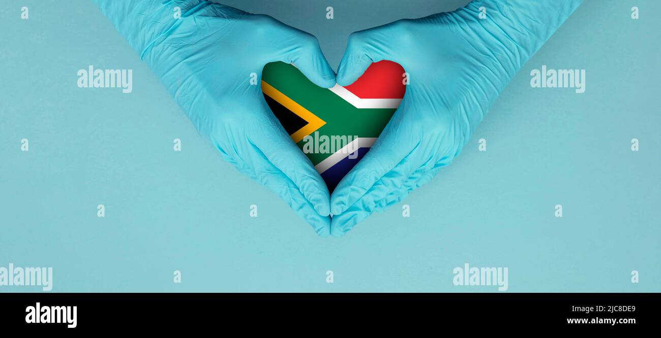 Doctors hands wearing blue surgical gloves making hear shape symbol with south africa flag Stock Photo