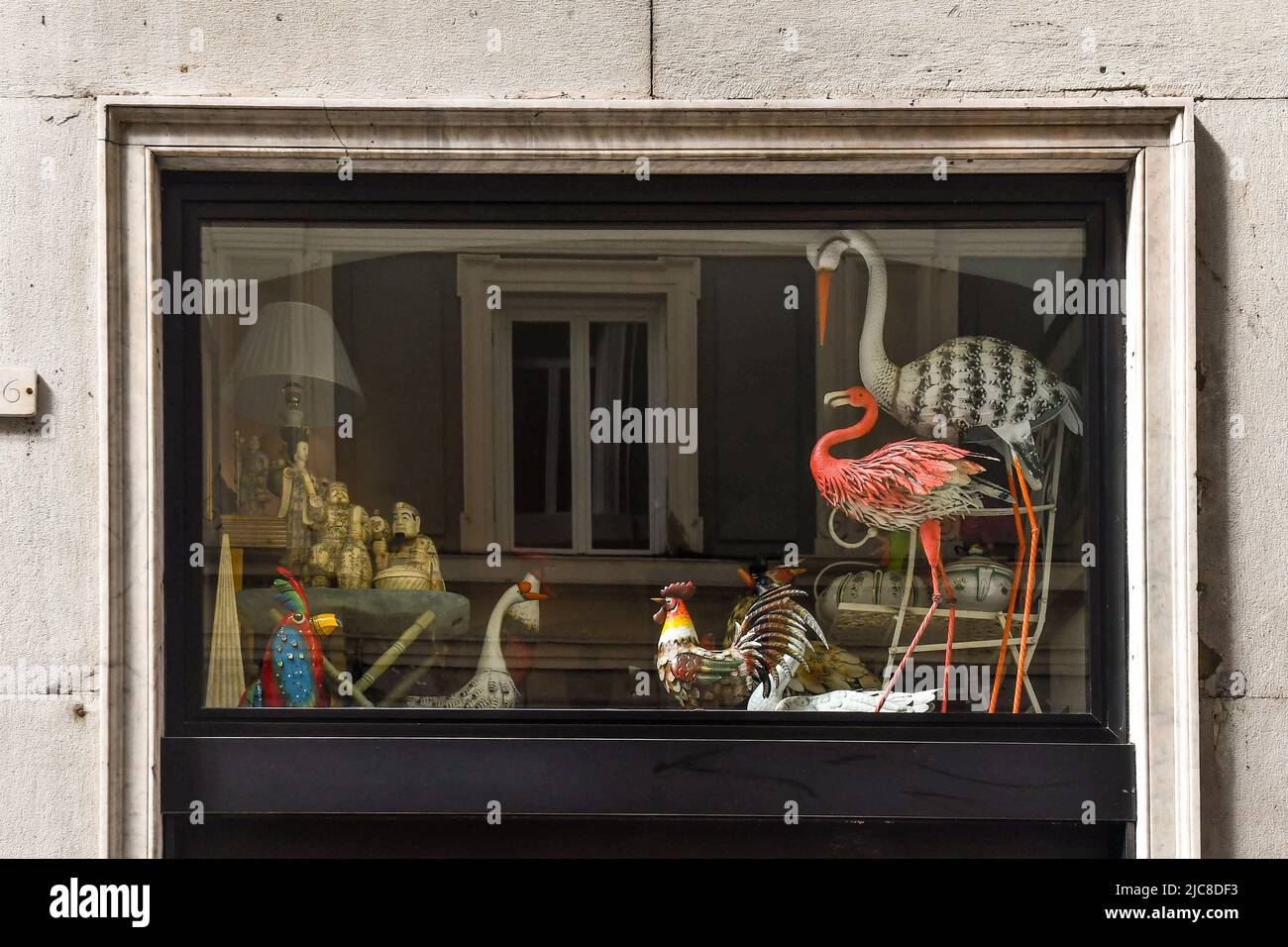 Close-up of the shop window of a gift shop with colorful objects representing different birds (cockerel, flamingo, heron...), Genoa, Liguria, Italy Stock Photo